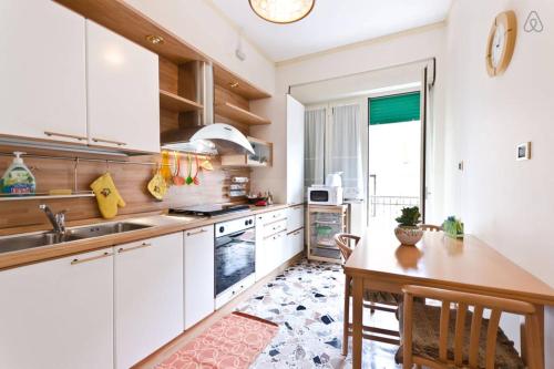 タオルミーナにあるAppartamento Vacanze Taorminaの白いキャビネットと木製テーブル付きのキッチン