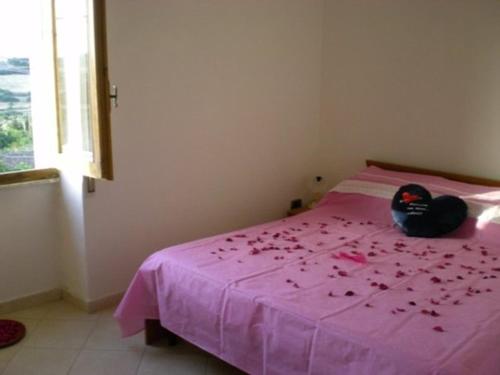 un animal de peluche sentado en una cama rosa con flores. en Apartment Da Mario, en Santa María