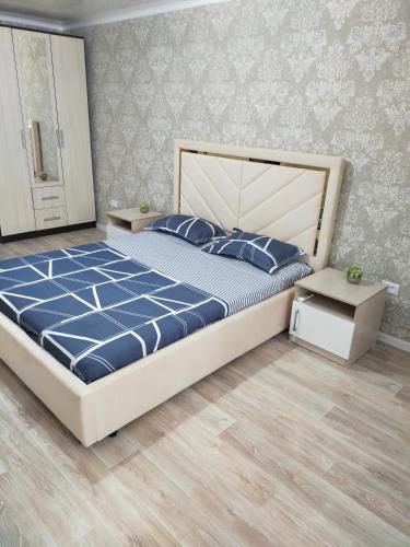 a bedroom with a large bed with a blue comforter at Vip квартира Центр in Uralsk