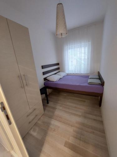 - une petite chambre avec un lit violet et une fenêtre dans l'établissement APARTMAN ADA, à Čukarica