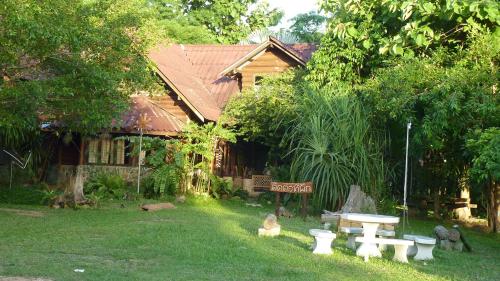 a garden with a picnic table and benches in front of a house at Baandin Chiewlarn in Ban Ta Khun