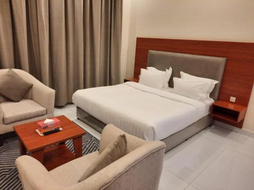 a hotel room with a bed and two chairs at المهيدب للشقق المخدومة - اقتصادى in Buraydah