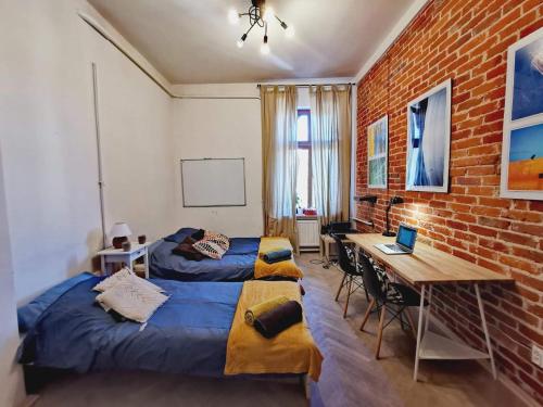 a bedroom with two beds and a desk and a brick wall at Smart Hostel Olsztyn in Olsztyn