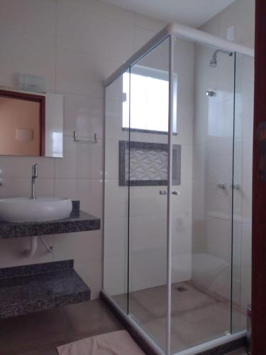 a bathroom with a glass shower and a sink at Pousada dos Pássaros in Quartéis