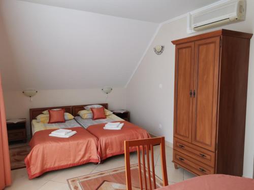 a bedroom with a bed and a wooden cabinet at Harmónia Panzió in Sárospatak