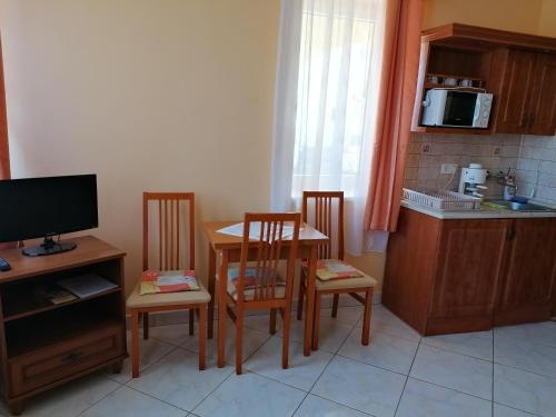 a kitchen with a table and two chairs and a television at Harmónia Panzió in Sárospatak