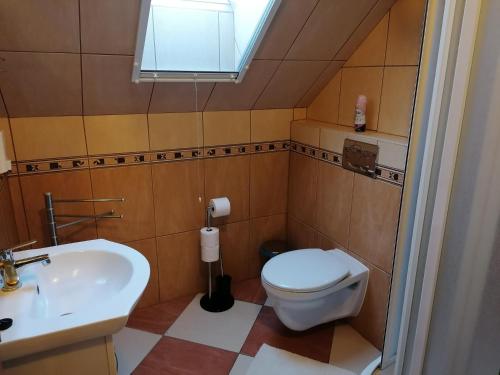 a bathroom with a toilet and a sink and a window at Harmónia Panzió in Sárospatak