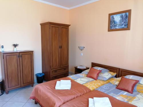 a bedroom with two beds and a wooden cabinet at Harmónia Panzió in Sárospatak