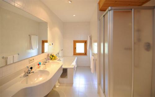a white bathroom with a sink and a shower at Pension Laurin in Schenna