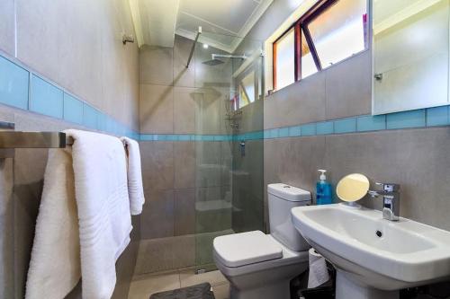 een badkamer met een toilet, een wastafel en een douche bij Unit 2a @ The Thatches in Kei Mouth