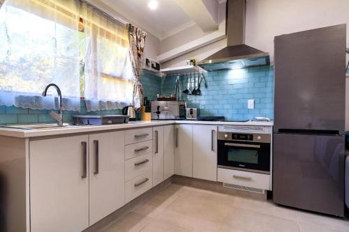 a kitchen with white cabinets and a stainless steel refrigerator at Unit 2a @ The Thatches in Kei-mouth Village