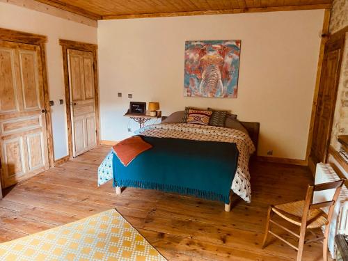 een slaapkamer met een bed en een schilderij aan de muur bij L'instant présent in Echallon