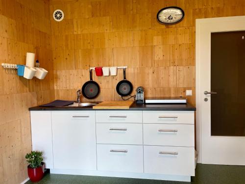 a kitchen with white cabinets and a clock on the wall at Ferien in Holz - Fühle die Gemütlichkeit Enjoy in Schörfling