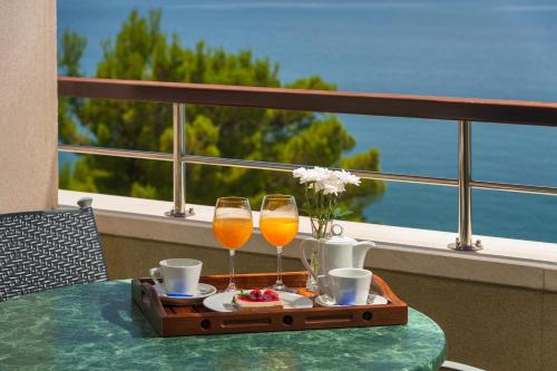 een dienblad met twee glazen wijn op een tafel bij Hotel Saudade in Gradac