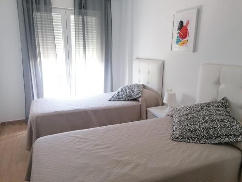 um quarto com 2 camas e uma janela em Agradable casa adosada con piscina em Zahara de los Atunes