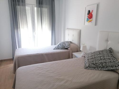 sypialnia z dwoma łóżkami i oknem w obiekcie Agradable casa adosada con piscina w mieście Zahara de los Atunes