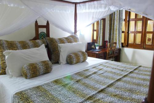 a bedroom with a large white bed with pillows at Tembo Court Apartments in Malindi