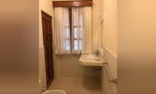 La salle de bains est pourvue d'un lavabo, de toilettes et d'une fenêtre. dans l'établissement Tembo Court Apartments, à Malindi