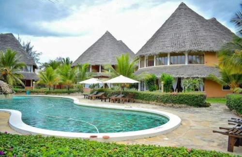 a resort with a swimming pool with tables and umbrellas at Tembo Court Apartments in Malindi