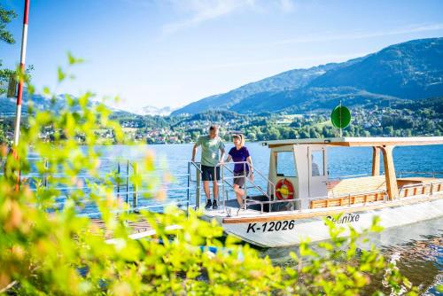 two people standing on a boat on the water at Pension Linder in Seeboden