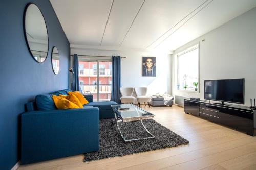 a living room with a blue couch and a tv at Arctic Homes - Premium Tromsø Residence in Tromsø