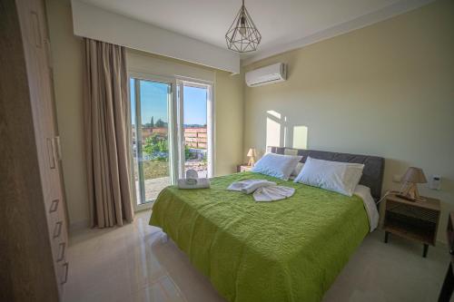 una camera da letto con un letto con una coperta verde e una finestra di Augoustinos Luxury Villa a Sarakinádhon