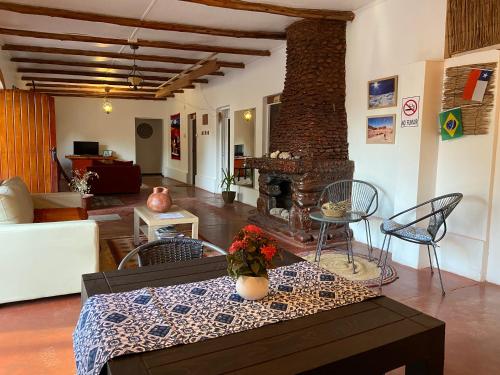 een woonkamer met een tafel en een open haard bij CaminAndes Hostal in San Pedro de Atacama