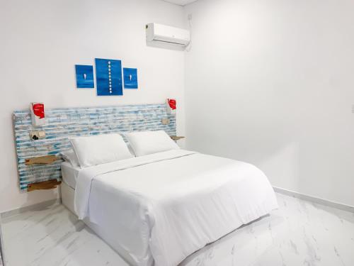 a white bedroom with a white bed and a blue wall at Fins Dive and Leisure Hotel in Rasdu