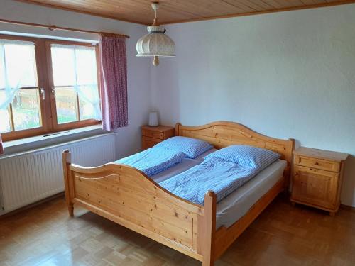 1 Schlafzimmer mit einem Holzbett und 2 Fenstern in der Unterkunft ruhig gelegene Allgäuer Ferienwohnung in Scheidegg