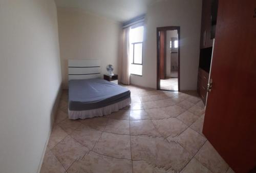 1 dormitorio con 1 cama y suelo de baldosa en suítes economy uberlandia, en Uberlândia