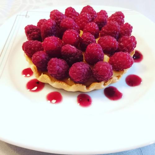 une assiette blanche recouverte de framboises au-dessus d'un dessert dans l'établissement Chambres d'hôtes Le Veilleur de Noblat, à Saint-Léonard-de-Noblat