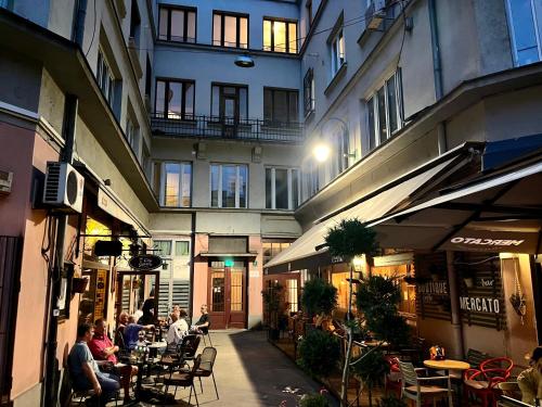 un gruppo di persone sedute ai tavoli fuori da un edificio di Apartmani Grand Market a Sarajevo