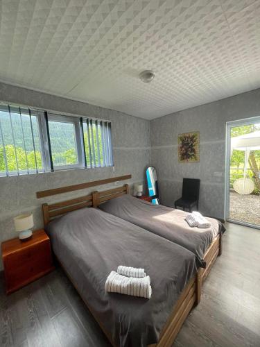 a bedroom with a large bed in a room with windows at Cottage - Location Lanchvali in Mestia
