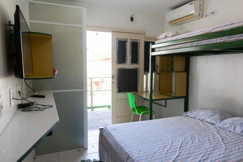 a bedroom with a bed and a desk with a green chair at FLAT ACONCHEGANTE in Teresina