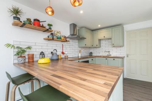 a kitchen with green cabinets and a wooden counter top at Beach, hills, food, scenic walks-The Kelp house. in Peacehaven