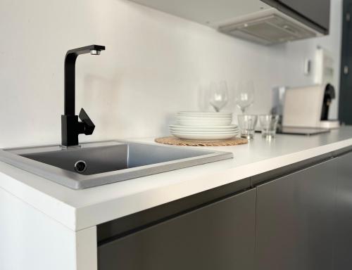 a kitchen counter with a sink and plates and glasses at Plasencia Plaza Mayor Luxury in Plasencia