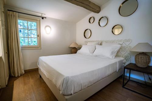 - une chambre avec un lit blanc et des miroirs sur le mur dans l'établissement Villa Les Muscadines Saint Tropez, Plage de Tahiti Pampelonne, à Saint-Tropez