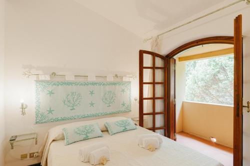 1 dormitorio con 1 cama con 2 almohadas y ventana en [PORTO CERVO MARINA] Incantevole appartamento vista Yacht en Porto Cervo