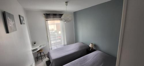 une petite chambre avec deux lits et une fenêtre dans l'établissement Appartement 2 chambres Balcon Parking privé Centre Village, à Lit-et-Mixe