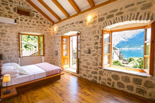ein Schlafzimmer mit einem Bett in einem Zimmer mit Fenstern in der Unterkunft GuestHouse Mrshe Palace in Perast