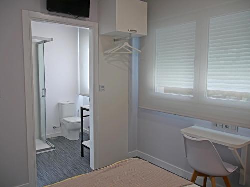 a bathroom with a window and a sink and a toilet at Siaba Pensión Boutique in Sigüeiro