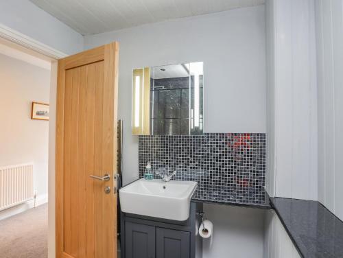 uma casa de banho com um lavatório e um espelho em Llety Ednyfed em Criccieth