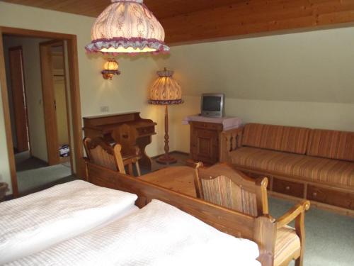 a room with two beds and a couch and a table at Pension Bergseeblick in Titisee-Neustadt