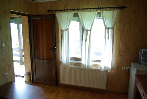 a room with a door and a window with curtains at Guest House Dan Kolov in Syennik