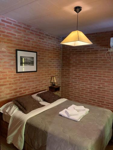 a bedroom with a bed with a brick wall at La Osadia Cabañas y Suites Solo Adultos in Mina Clavero