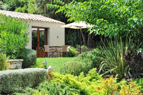 a garden with a table and an umbrella at Résidence Sophia in Bonifacio