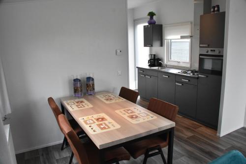 une cuisine avec une table et des chaises ainsi qu'une cuisine avec une cuisinière dans l'établissement Chalet ‘Het Giethoornsche Meer’ (16), à Giethoorn