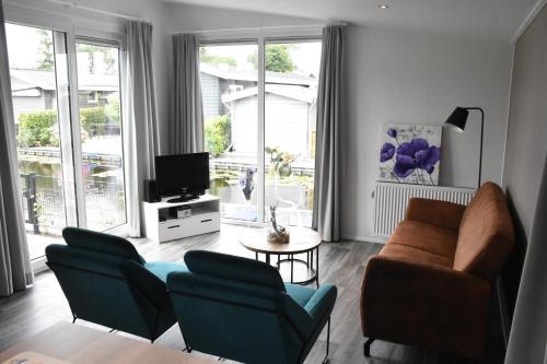 een woonkamer met een bank en stoelen en een televisie bij Chalet ‘Het Giethoornsche Meer’ (16) in Giethoorn