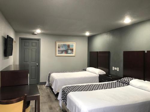ニスビルにあるBudget Inn Valparaiso/Niceville @ Eglin AFB & Destin-FWB Airportのベッド2台、テーブルと椅子が備わるホテルルームです。