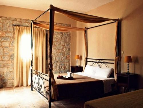 1 dormitorio con cama con dosel y ventana en Vlyhada Guesthouse, en Pyrgos Dirou